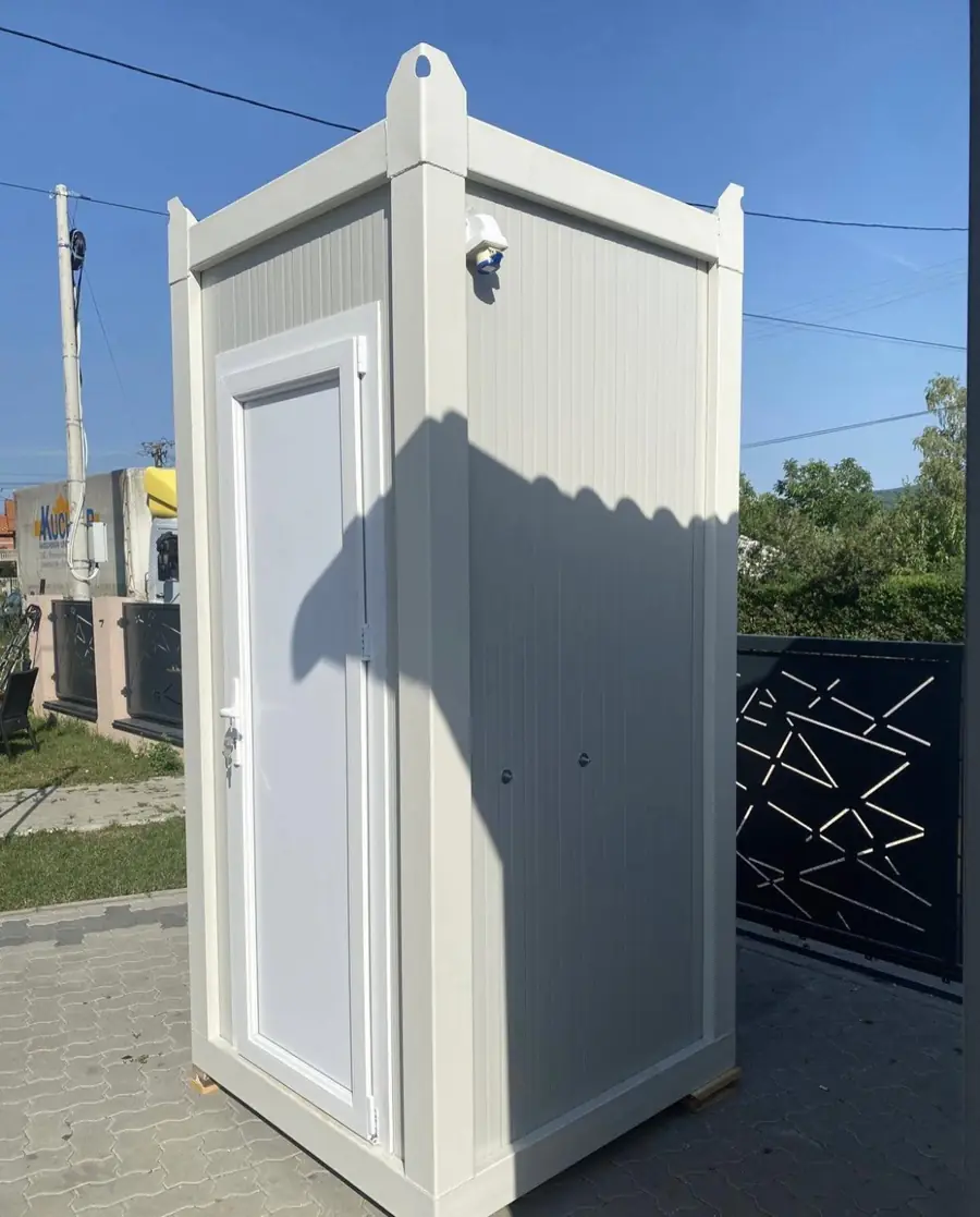 White single-stall flushing restroom cabin outside a home