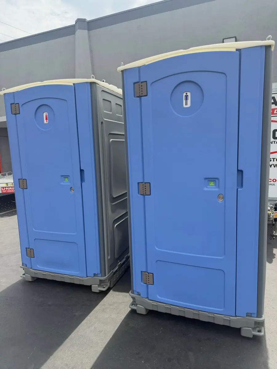 Two blue standard porta potties set side by side on pavement
