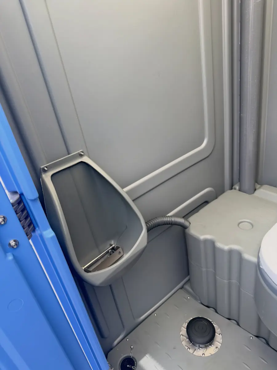 Inside a standard porta potty showing the urinal and toilet paper holder
